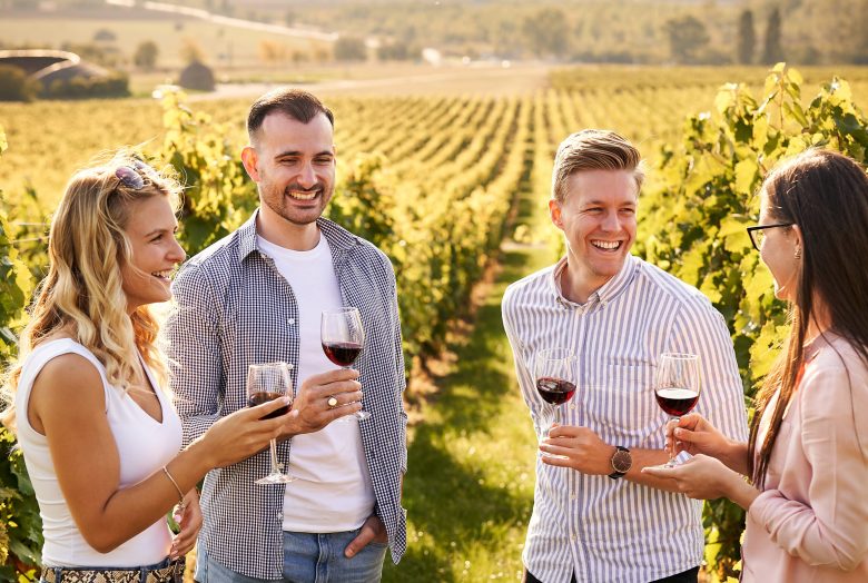 Young friends having fun outdoors - Happy people enjoying harvest time together at farmhouse winery countryside - Tasting red wine at vineyard